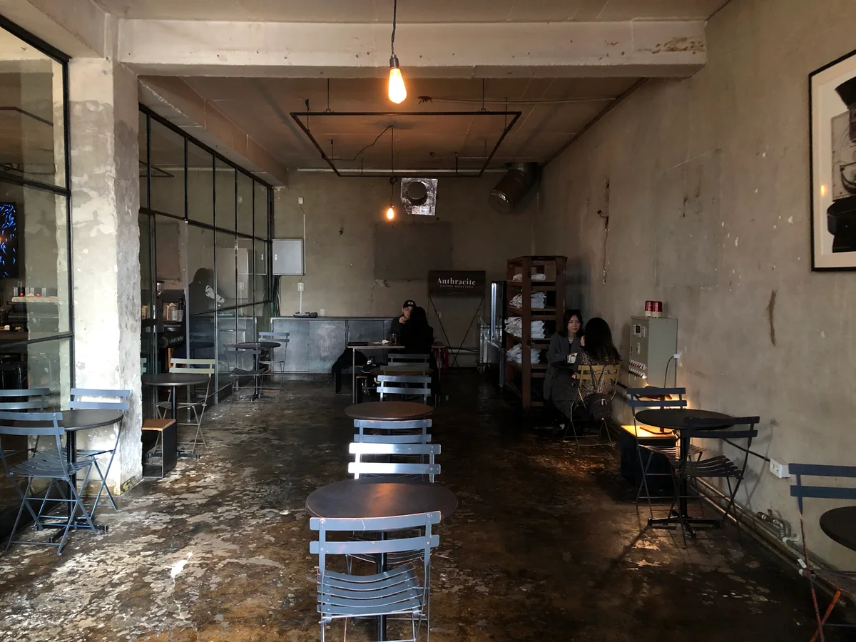 Exposed concrete and glass partitions inside Anthracite’s Hapjeong café