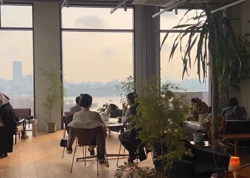 Visitors sit beside broad river-facing windows at Bean Brothers Coffeehouse Seoul in Sangsu.