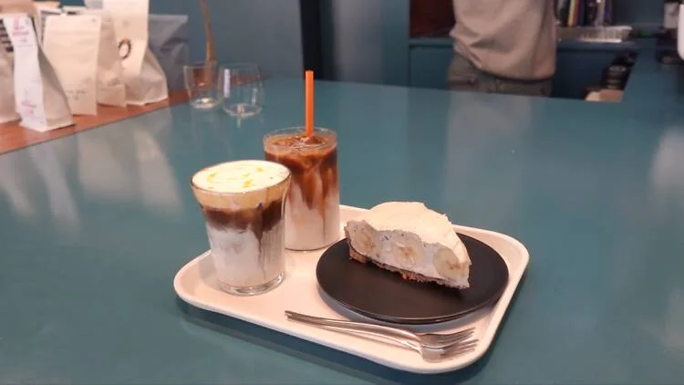 Coffee and a slice of cake on a blue table at Flick On Coffee in Sinchon.