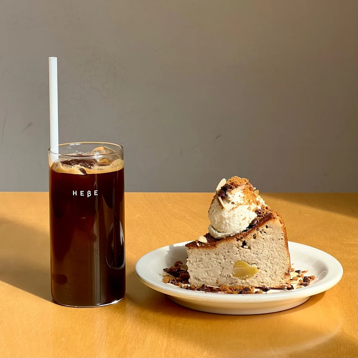 Hebe-branded iced black coffee beside a slice of chestnut cheesecake at the Chungmuro shop.