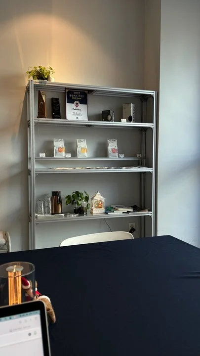 Shelves, coffee equipment and a communal table inside Hooroop Roasters Magok