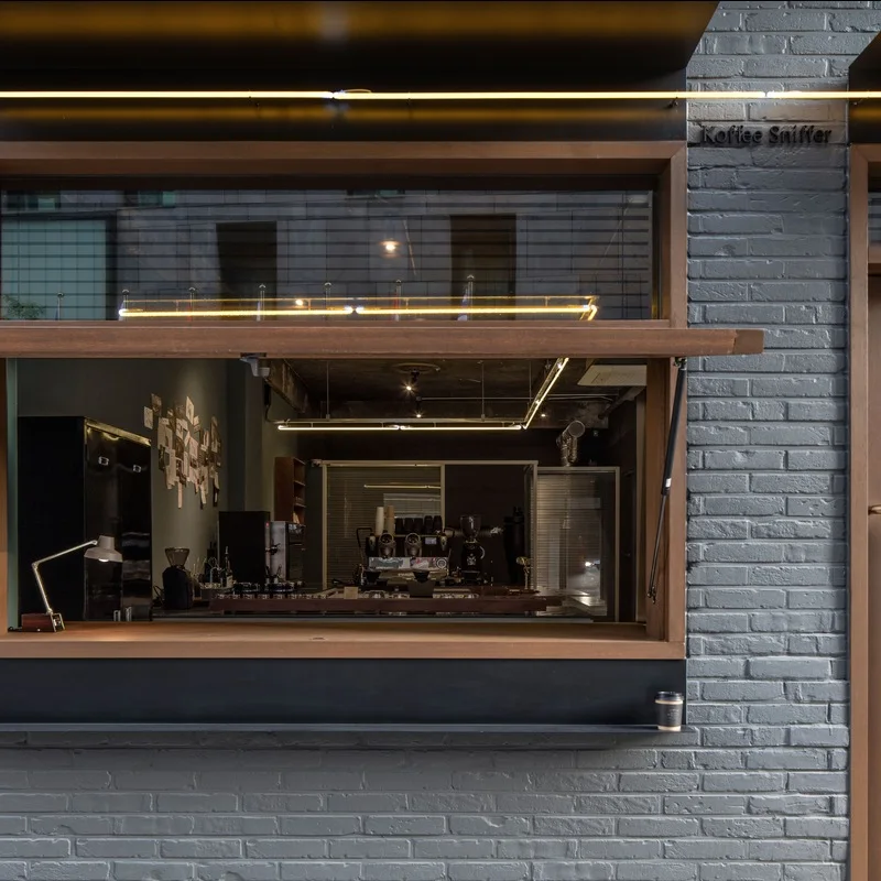 Dark brick frontage and service window with Koffee Sniffer lettering at the City Hall branch.
