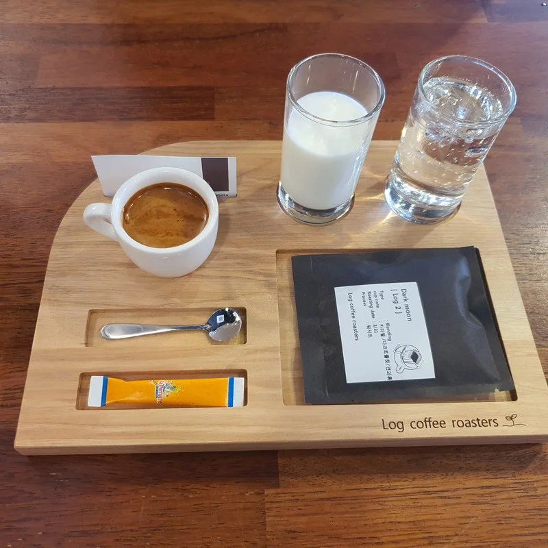 Espresso, milk and water served on a branded wooden tray at Log Coffee Roasters