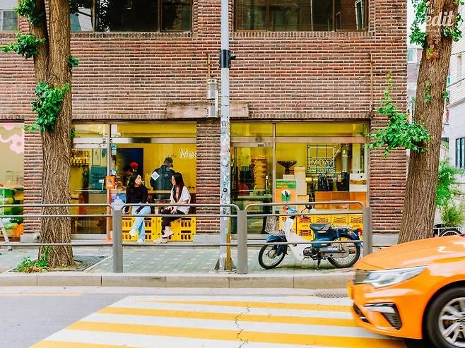 Mesh Coffee’s original Seongsu storefront with trees and an orange taxi