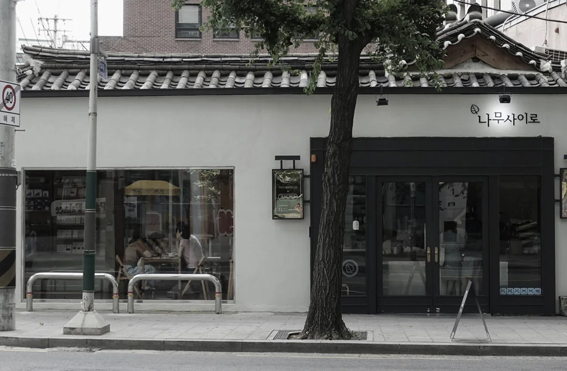 Namusairo’s white façade, tiled hanok roof and street tree in Naeja-dong