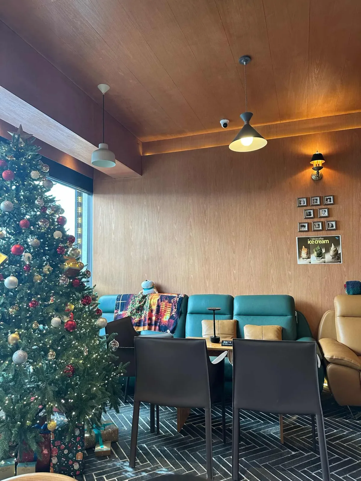 Wood-paneled seating, pendant lamps and a seasonal tree inside Tahoe Coffee Ahyeon.