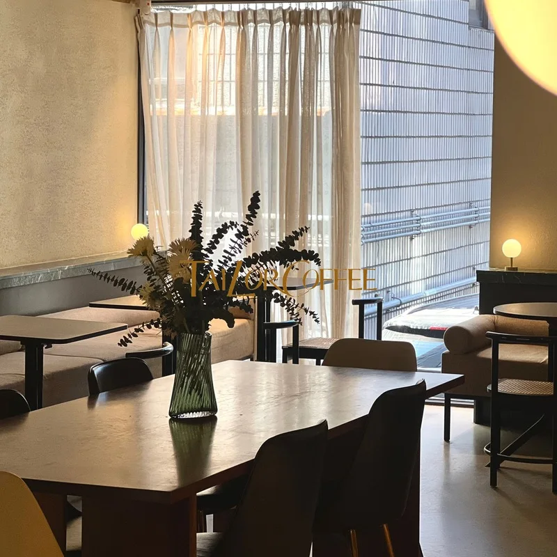 Wooden tables, pale tiles and window light inside Tailor Coffee Sinsa